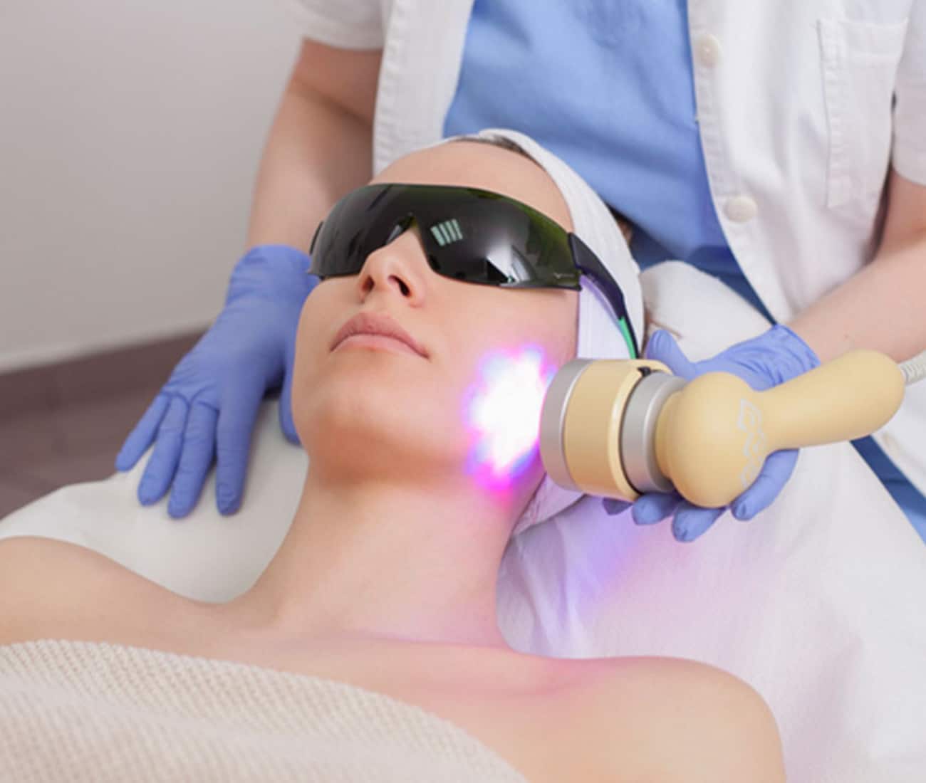 a person lying on a bed receiving intense pulsed light treatment on face